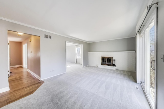 unfurnished living room featuring visible vents, baseboards, a glass covered fireplace, and ornamental molding