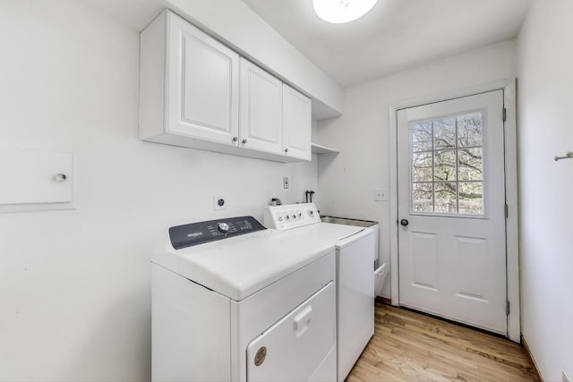 laundry area featuring light wood finished floors, cabinet space, and washer and clothes dryer