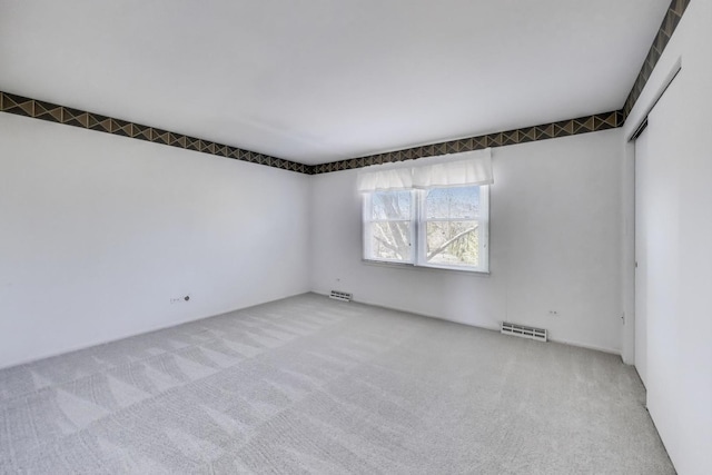 carpeted empty room featuring visible vents