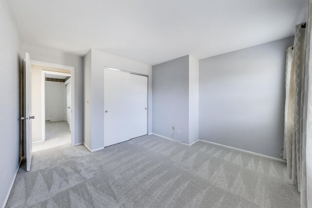 unfurnished bedroom featuring carpet flooring, baseboards, and a closet