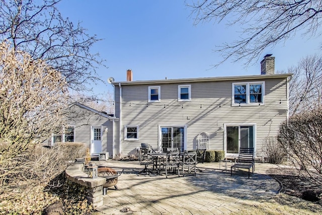 rear view of house featuring a fire pit, a chimney, and a patio