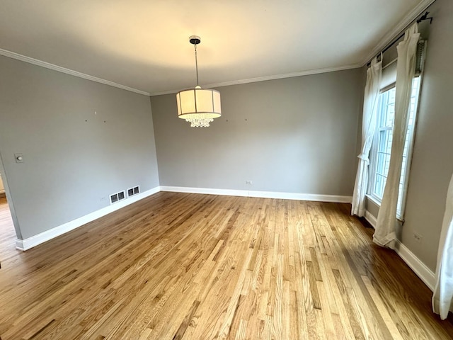 unfurnished room with visible vents, crown molding, baseboards, and wood finished floors