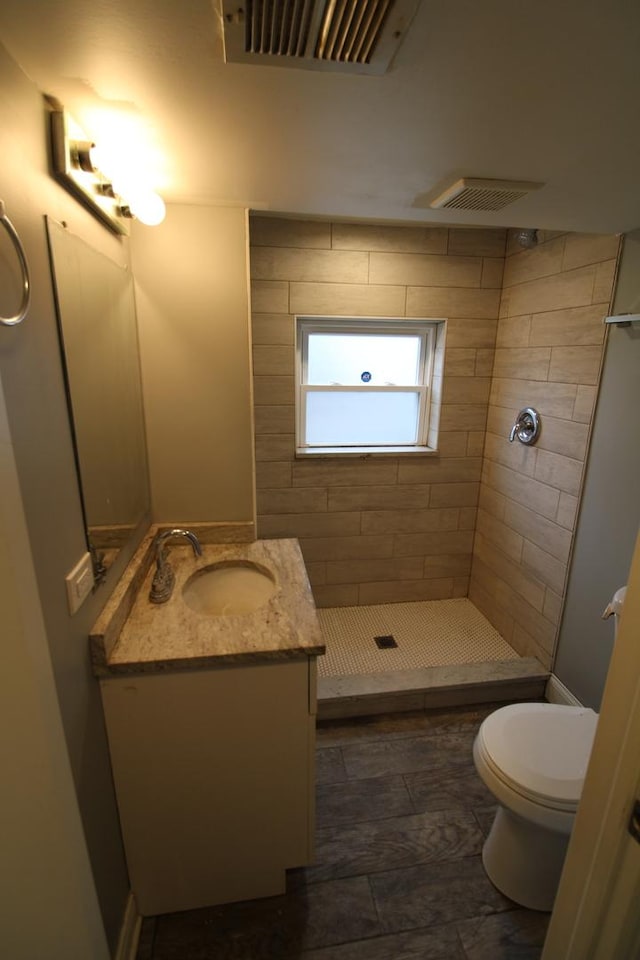 bathroom with toilet, vanity, and tiled shower