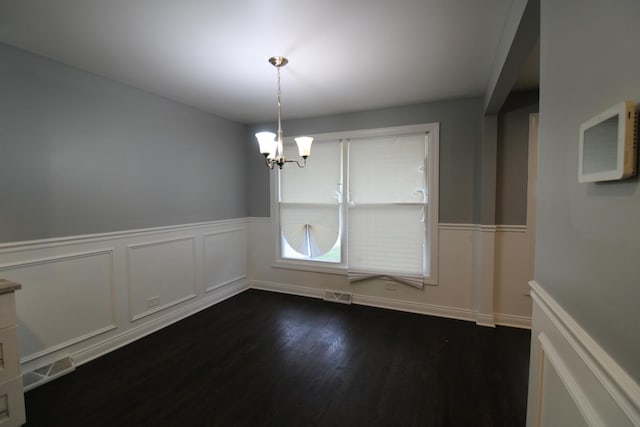 unfurnished dining area featuring a notable chandelier and dark hardwood / wood-style flooring