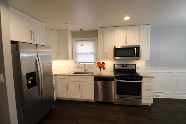 kitchen featuring decorative light fixtures, sink, white cabinetry, and appliances with stainless steel finishes