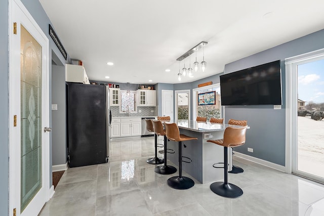 kitchen featuring appliances with stainless steel finishes, backsplash, hanging light fixtures, plenty of natural light, and white cabinets