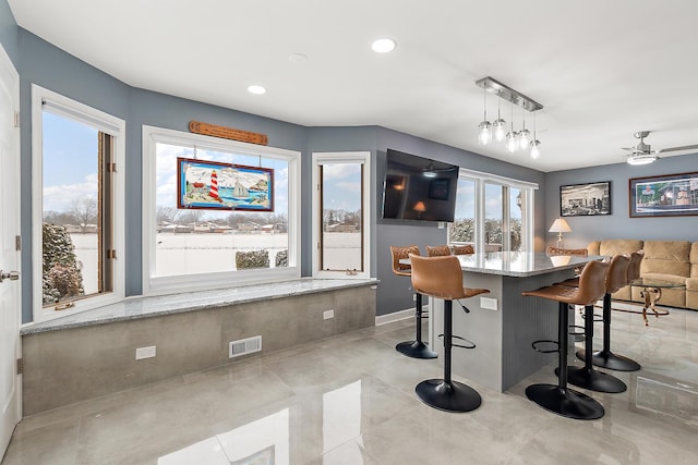 interior space with light stone counters, hanging light fixtures, and ceiling fan