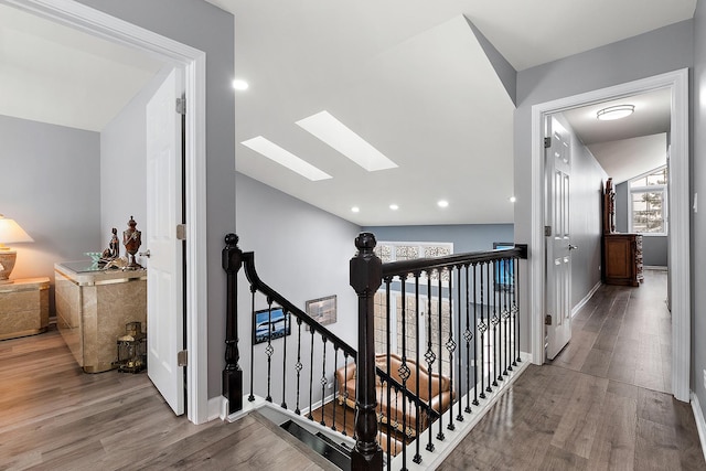 hall featuring hardwood / wood-style flooring and lofted ceiling with skylight