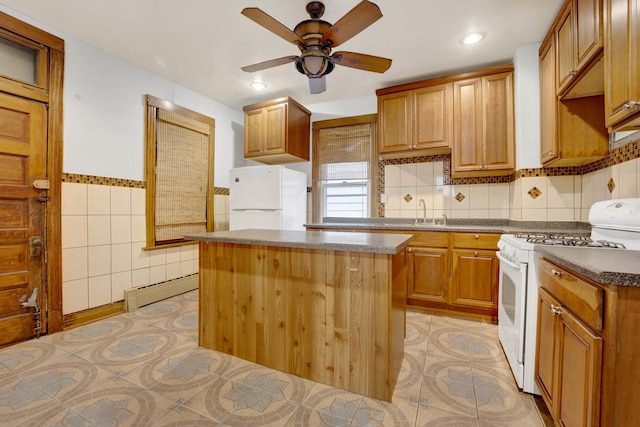 kitchen with ceiling fan, white appliances, baseboard heating, a kitchen island, and sink