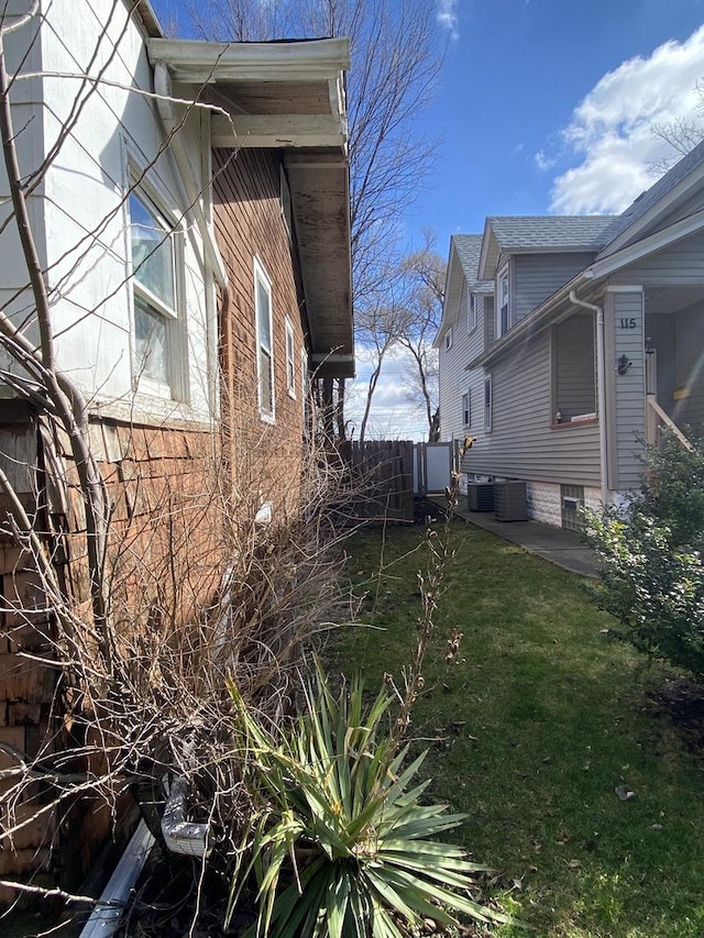 view of side of property featuring a yard and central AC