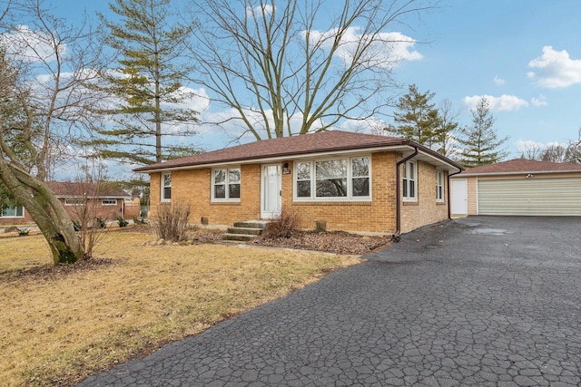 view of front of property featuring an outbuilding, brick siding, a front yard, and a garage