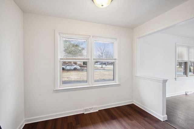 spare room with baseboards, visible vents, and dark wood finished floors