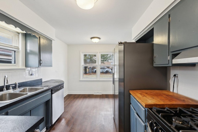 kitchen with dishwasher, butcher block counters, dark wood-style flooring, a sink, and backsplash