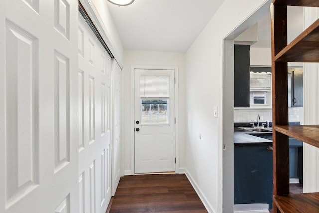 doorway featuring a sink, dark wood finished floors, and baseboards