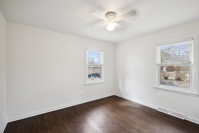 spare room featuring a ceiling fan, dark wood-style flooring, visible vents, and baseboards