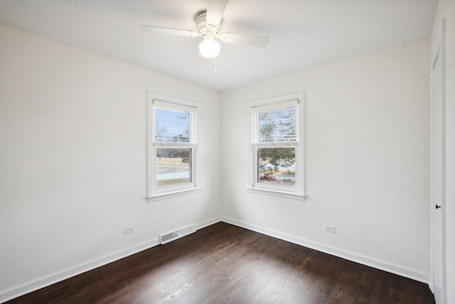 spare room with ceiling fan, baseboards, visible vents, and dark wood finished floors