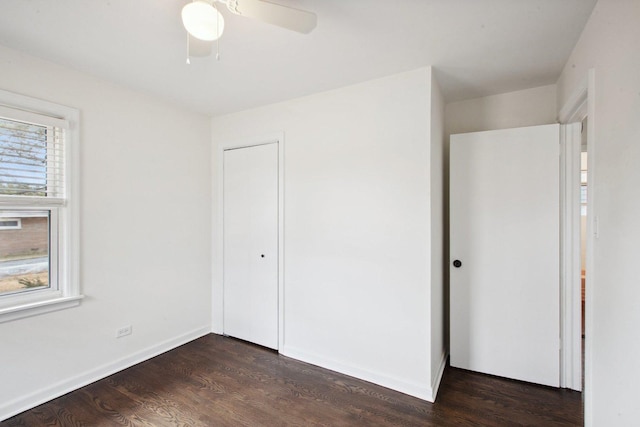 unfurnished bedroom with ceiling fan, dark wood-type flooring, a closet, and baseboards