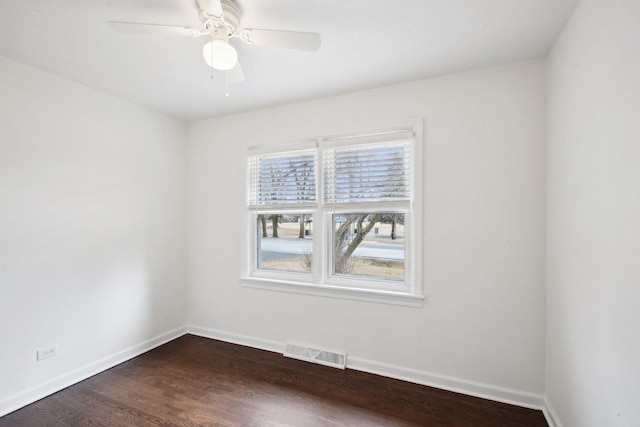 empty room featuring dark wood-style floors, visible vents, and baseboards