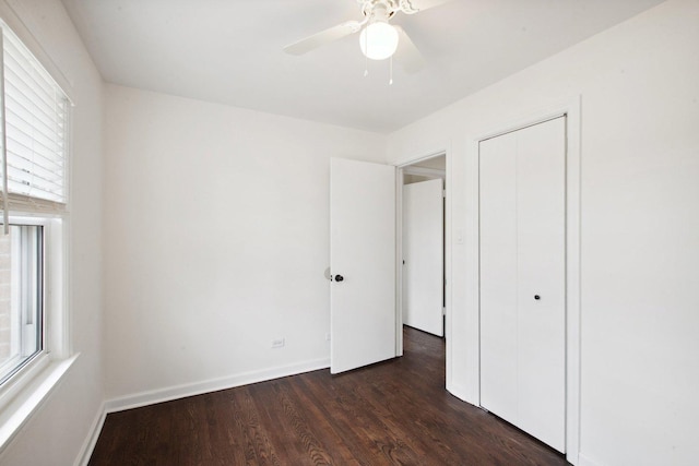 unfurnished bedroom with a ceiling fan, a closet, baseboards, and dark wood-type flooring