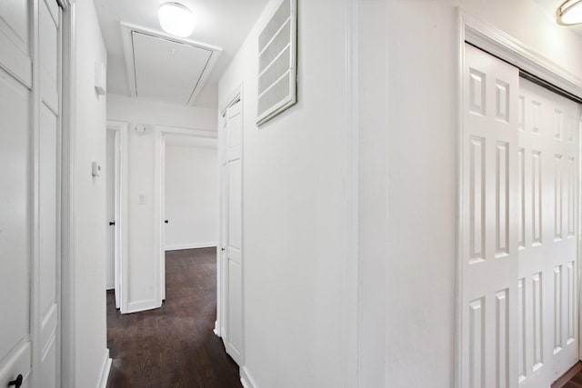 corridor with dark wood-style floors, attic access, and baseboards