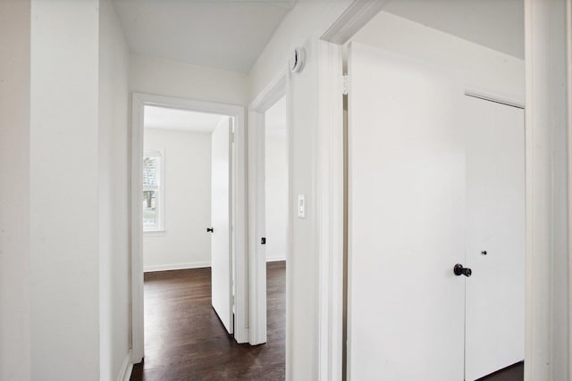 corridor featuring dark wood-style floors and baseboards