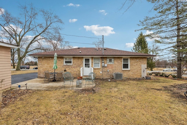 rear view of house featuring brick siding, central AC unit, a lawn, and a patio