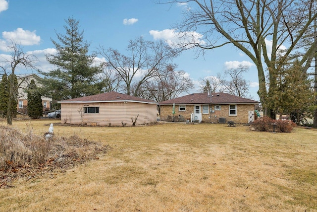 back of house featuring brick siding and a lawn