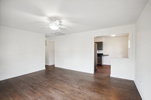 unfurnished room featuring dark wood-style floors, ceiling fan, visible vents, and baseboards