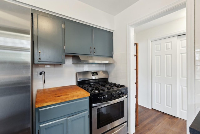 kitchen featuring tasteful backsplash, dark wood finished floors, butcher block countertops, stainless steel appliances, and under cabinet range hood