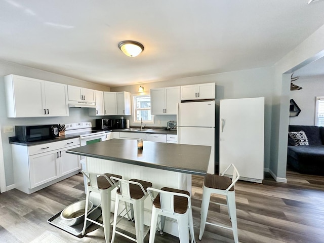 kitchen with sink, a kitchen bar, white cabinets, and white appliances