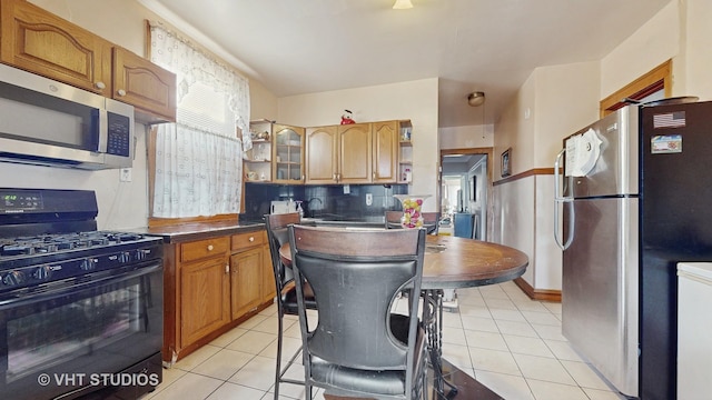 kitchen with light tile patterned flooring, stainless steel appliances, decorative backsplash, and plenty of natural light