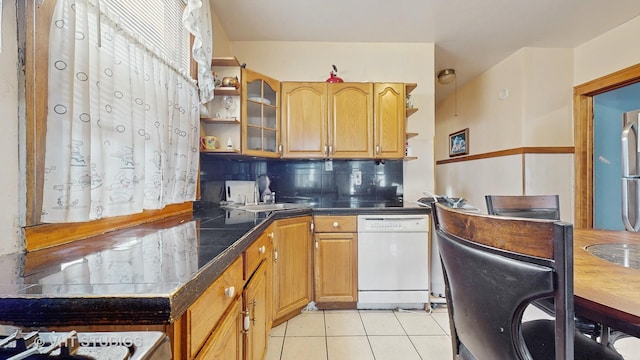 kitchen with backsplash, white dishwasher, sink, and light tile patterned floors