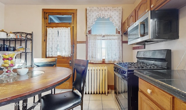 kitchen featuring light tile patterned flooring, black range with gas stovetop, and radiator