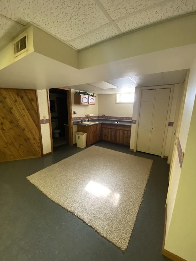 kitchen with a paneled ceiling, kitchen peninsula, and wood walls