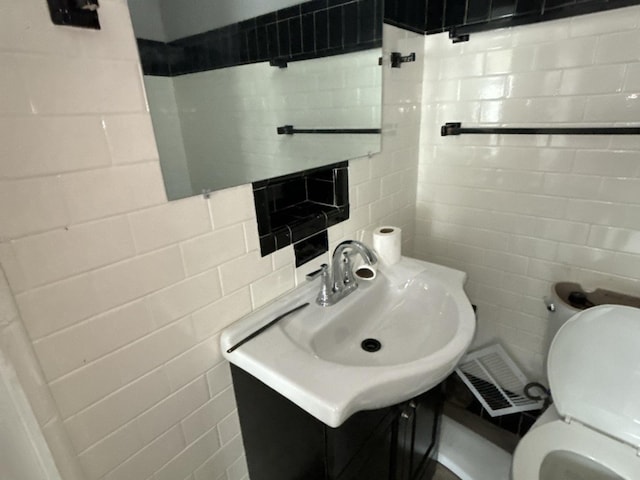 bathroom featuring vanity, toilet, tile walls, and tasteful backsplash