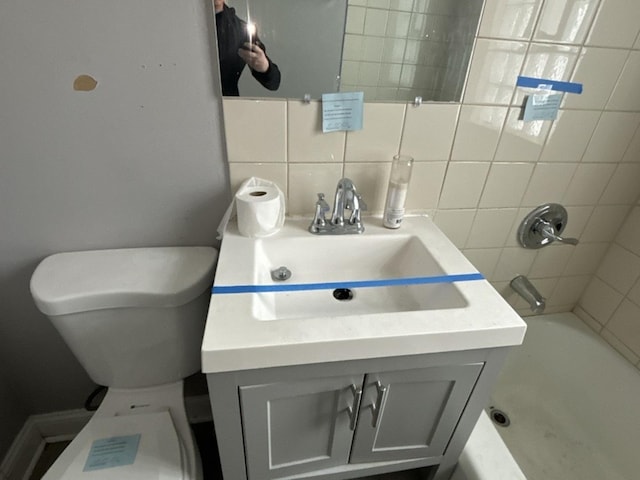 full bathroom featuring vanity, toilet, tiled shower / bath, and decorative backsplash