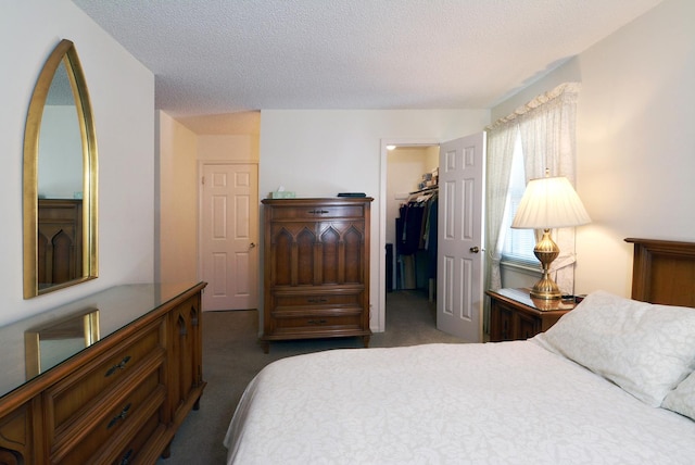 bedroom featuring carpet floors, a walk in closet, a closet, and a textured ceiling