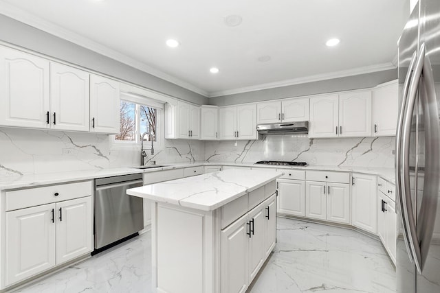 kitchen featuring appliances with stainless steel finishes, sink, white cabinets, light stone countertops, and a center island