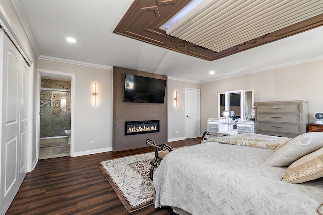 bedroom with a large fireplace, a closet, ornamental molding, dark wood-type flooring, and connected bathroom