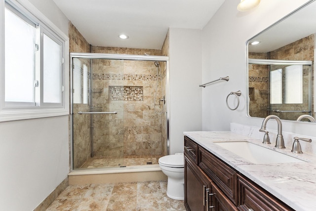 bathroom with vanity, toilet, and a shower with door