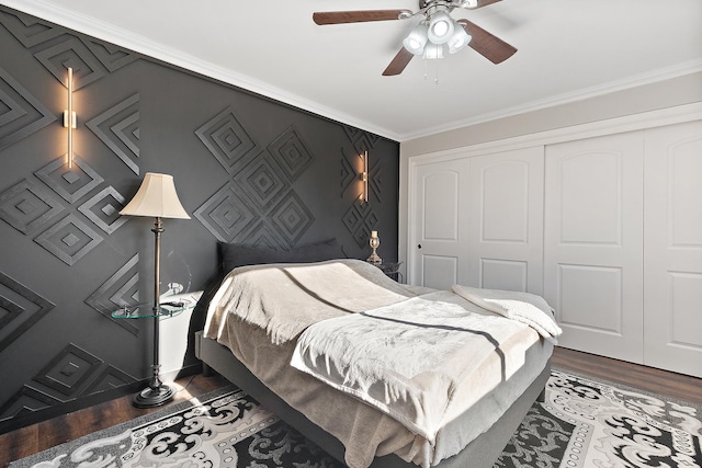 bedroom with a closet, ceiling fan, crown molding, and dark hardwood / wood-style floors