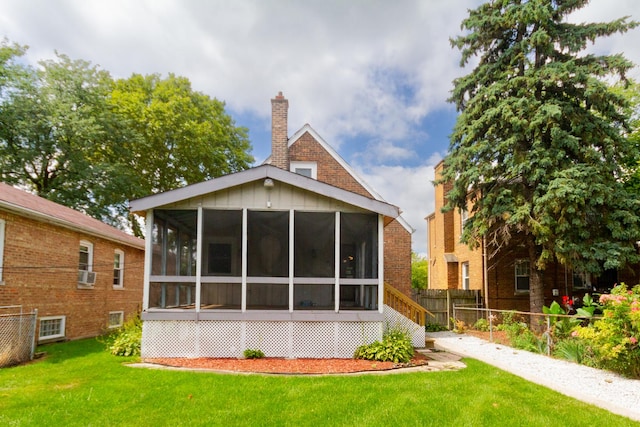 rear view of house with a sunroom and a yard