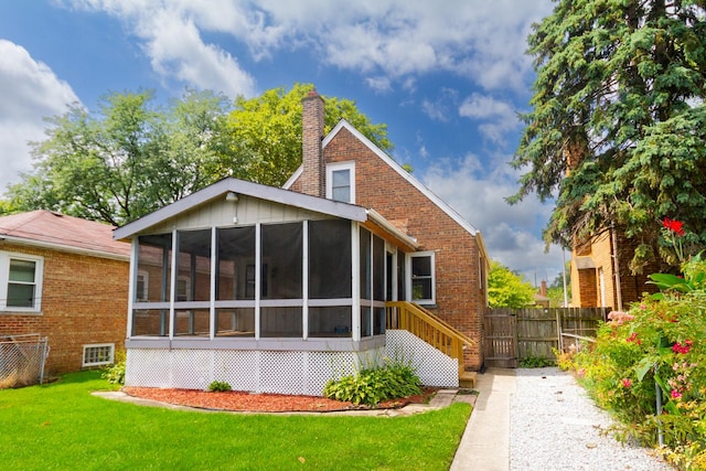 rear view of property featuring a sunroom and a yard