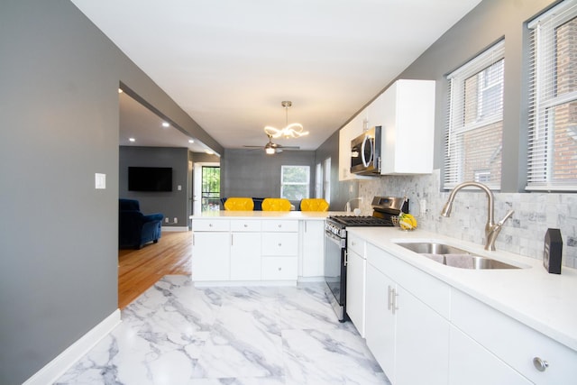 kitchen with stainless steel appliances, sink, white cabinets, and decorative light fixtures