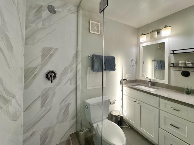 bathroom featuring vanity, toilet, and tiled shower