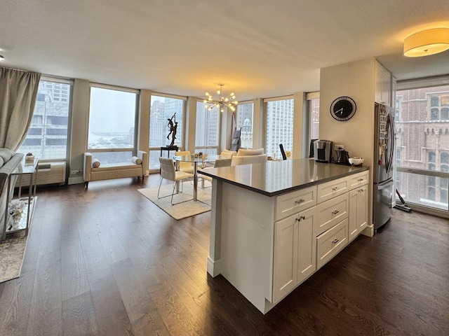 kitchen with stainless steel refrigerator, white cabinetry, dark hardwood / wood-style flooring, hanging light fixtures, and an inviting chandelier