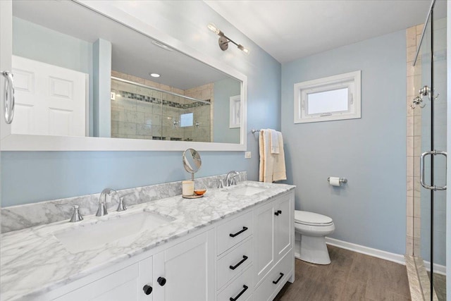 bathroom featuring wood-type flooring, toilet, a shower with door, and vanity