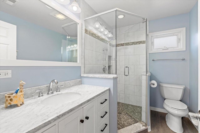 bathroom with toilet, wood-type flooring, an enclosed shower, and vanity