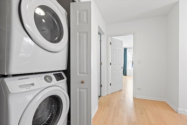 washroom with light hardwood / wood-style flooring and stacked washing maching and dryer