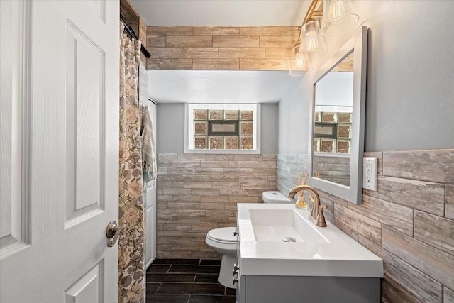 bathroom featuring plenty of natural light, tile walls, toilet, and vanity